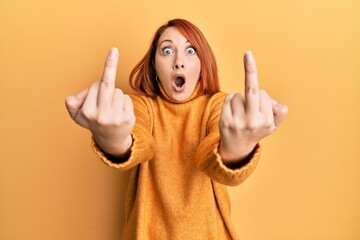 Wall Mural - Beautiful redhead woman showing middle finger doing bad gesture afraid and shocked with surprise and amazed expression, fear and excited face.