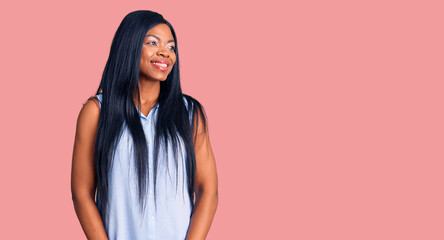 Poster - Young african american woman wearing casual clothes looking away to side with smile on face, natural expression. laughing confident.