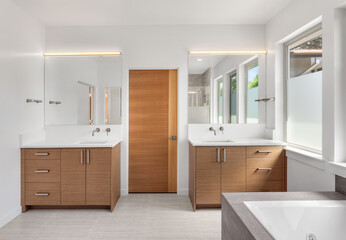 Bathroom in luxury home with double vanity, mirror, sink, and tile floor. Also shows large soaking bathtub