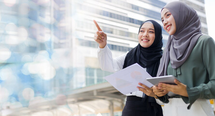 successful muslim businesswomen are discussing work to achieve common goals while outdoors.