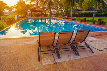 Wall Mural - Relaxing on a bench beside swimming pool during sunrise.