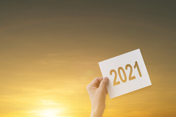 Silhouette of hand-holding paper with 2021 text for Happy New Year 2021.