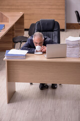 Old male employee drinking coffee during break