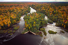 Beautiful Aerial Of The Lower Waterfall Cascades On The Tahquamenon River Surrounded By Evergreen And Fall Foliage Colored Deciduous Trees With Yellow, Green, Red And Orange Leaves In Upper Michigan.