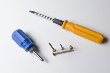 two different screwdrivers and several screws on a white background. close-up.