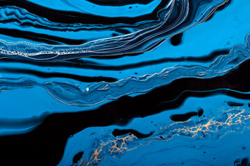 Fluid Art. Golden wave in abstract ocean of blue paint. Marble effect background or texture