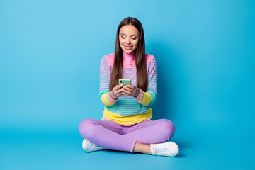 Poster - Portrait of lovely focused cheerful girl sitting lotus position crossed legs using app 5g isolated bright blue color background