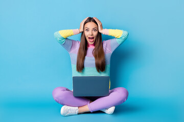 Wall Mural - Portrait of glad cheerful amazed girl sitting lotus position crossed legs using laptop great news isolated on bright blue color background