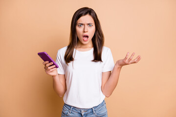 Photo portrait of young woman arguing angry shouting with mobile phone irritated isolated pastel beige color background