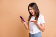 © deagreez - Photo portrait of mad furious girl shouting keeping cellphone angry crazy isolated pastel beige color background