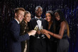 © Seventyfour - Waist up portrait of multi-ethnic group of friends clinking champagne glasses and smiling at camera while enjoying elegant party