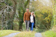 © goodluz - Mixed-raced couple enjoying walk in country path during autumn season