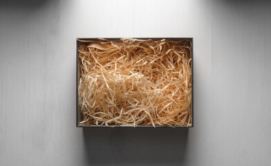 Top view of an open box with packing sawdust. Gift wrapping on the table.