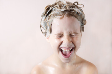 Wall Mural - a little blonde girl in the bathroom with foam on her head laughs happily with her mouth open