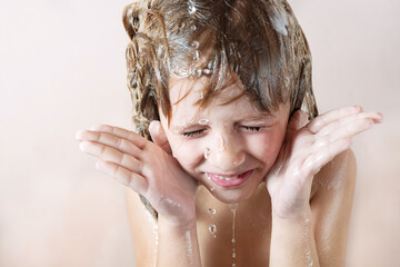 Wall Mural - charming little blonde girl washes her hair in the bathroom with foam on her head. water pours, drop