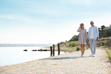 Wall Mural - Happy couple walking along waterfront on summer day