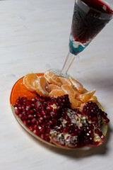 Wall Mural - Red wine glass and plate with mandarin and garnet on white background