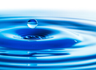 Dark blue water droplets splash in the water surface  close up. Creating a perfect water wave