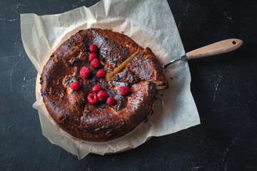 Wall Mural - Burnt hot cheese cake out of the oven on the parchment or baking paper at the black background.