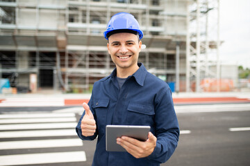 Worker using his tablet in front of a construction site