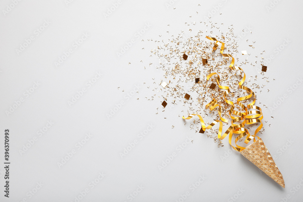 Golden confetti and streamers with party cracker on white background, top view. Space for text - obrazy, fototapety, plakaty 
