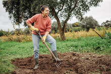 Female Farmer Digging Ground In Cloudy Autumn Day. Woman Working With Shovel In Field