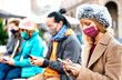 © Mirko Vitali - Blond girl using smart phone covered by mask on Covid second wave - New normal lifestyle concept with milenial people watching video on mobile smartphone - Vivid filter with focus on woman face