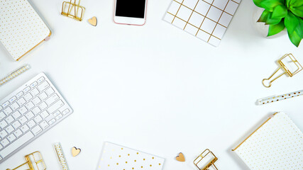 stylish white and gold theme desktop workspace with keyboard, notebooks and smart phone. top view bl