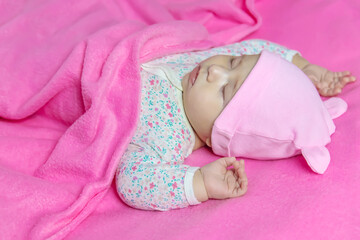 Poster - Baby sleeps on a pink bed. Selective focus.