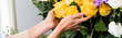 Cropped view of female florist caring about yellow roses near flowers in store, banner