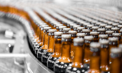 Glass bottles of beer on dark background with sun light. Concept brewery plant production line