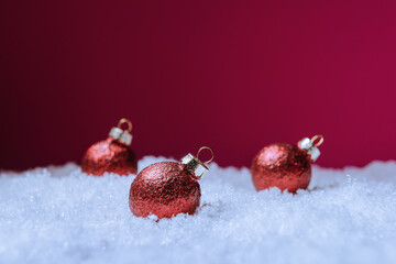 Wall Mural - Christmas balls in snow against pink background with copy space. New Year and Xmas greeting card