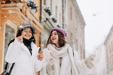 Smiling women celebrating winter holidays with sparklers