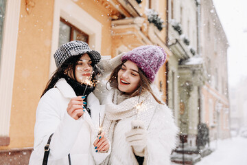 Joyful women using sparkles for celebrating winter holidays