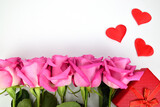 Fototapeta Tulipany - Roses are arranged in a row next to a red gift box and three decorative hearts.