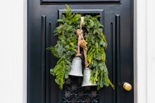 Christmas Wreath With Bells On Entrance Vintage Black Door Outside. Veranda Front Door Decorated By Christmas Festive Wreath Decor. Traditional Christmas Outdoor Exterior In Netherlands