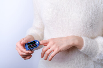 Person using pulse oximeter device on finger, healthcare monitoring concept