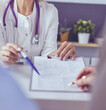 © lenets_tan - Doctor and patient examining a file with medical records, she is sitting on a wheelchair