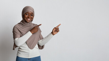 Look There. Black muslim lady in hijab pointing away with two hands