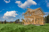 Fototapeta  - Frame of a cottage under construction against a beautiful sky. Construction of a private house in the countryside. Wooden country house under construction. Rural properties. New country houses.