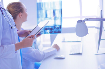 Wall Mural - Close up shoot of doctor with tablet and colleague with x-ray on the background.