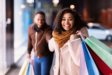 Excited Black Woman Pulling Boyfriend To Shopping Store