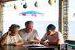 © sutthichai - Happy family.Happy couple of retirement parent enjoy in restuarant with their son for reading a food menu.