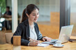 © amnaj - Charming asian businesswoman sitting working on laptop in office.