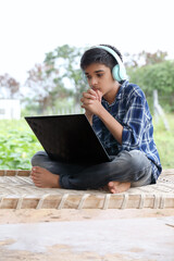 Sticker - Portrait of Indian boy using laptop while attending the online classes at home outside