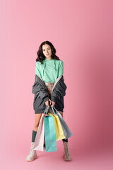 Wall Mural -  young woman in casual winter outfit with shopping bags on pink background