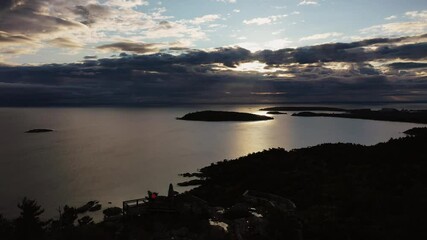 Wall Mural - Beautiful sunrise aerial panning out above Sugarloaf Mountain looking towards Presque Isle peninsula and islands in Lake Superior with the sun shining between clouds and reflecting off of the water.