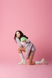 © LIGHTFIELD STUDIOS - side view of young woman in stylish winter outfit posing on floor on pink background