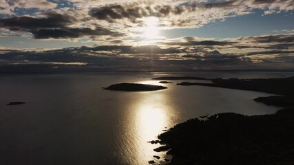 Wall Mural - Beautiful panning across sunrise aerial above Sugarloaf Mountain looking towards Presque Isle peninsula and islands in Lake Superior with the sun shining between clouds and reflecting off of the water