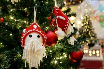 Wall Mural - Christmas tree with knitted toys on blurred lights background. New Year decorations in a shopping mall